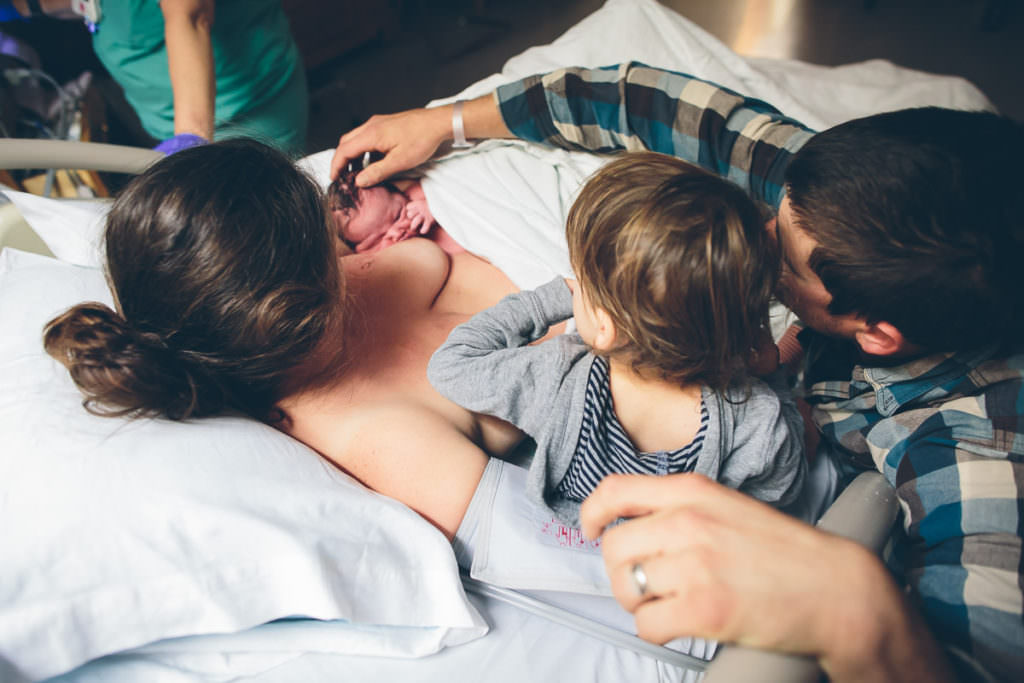 family of four meeting newborn brother right after his birth