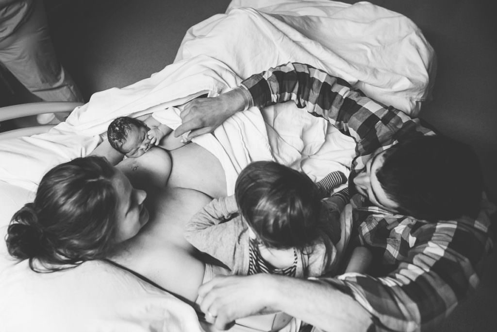 downward view of family of four on hospital bed after baby was born