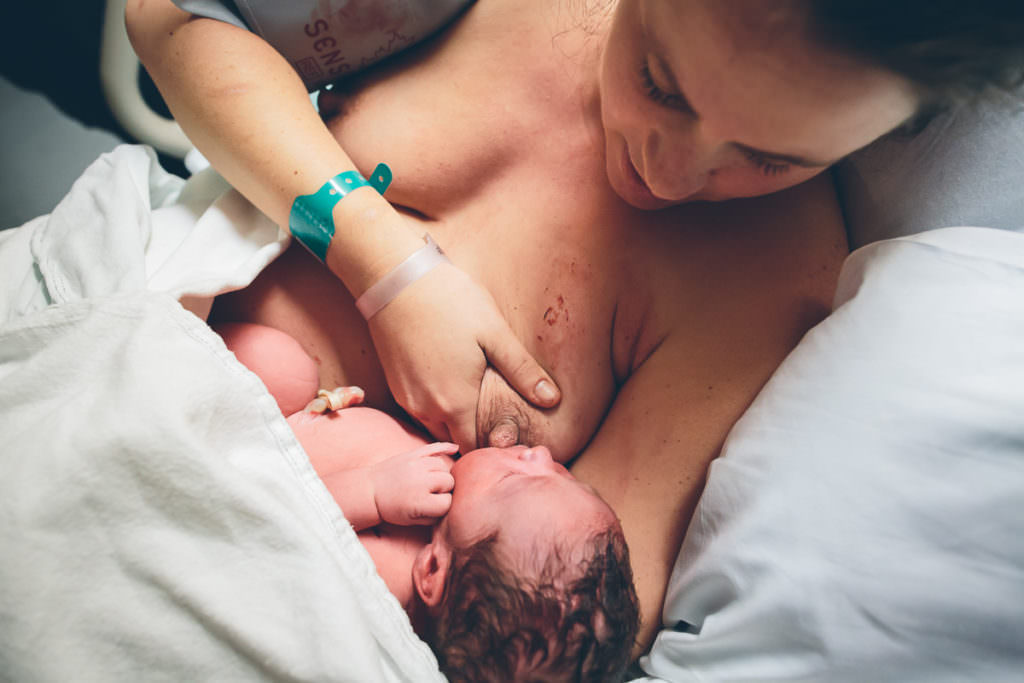 mom holding her breast getting ready to breastfeed her newborn baby