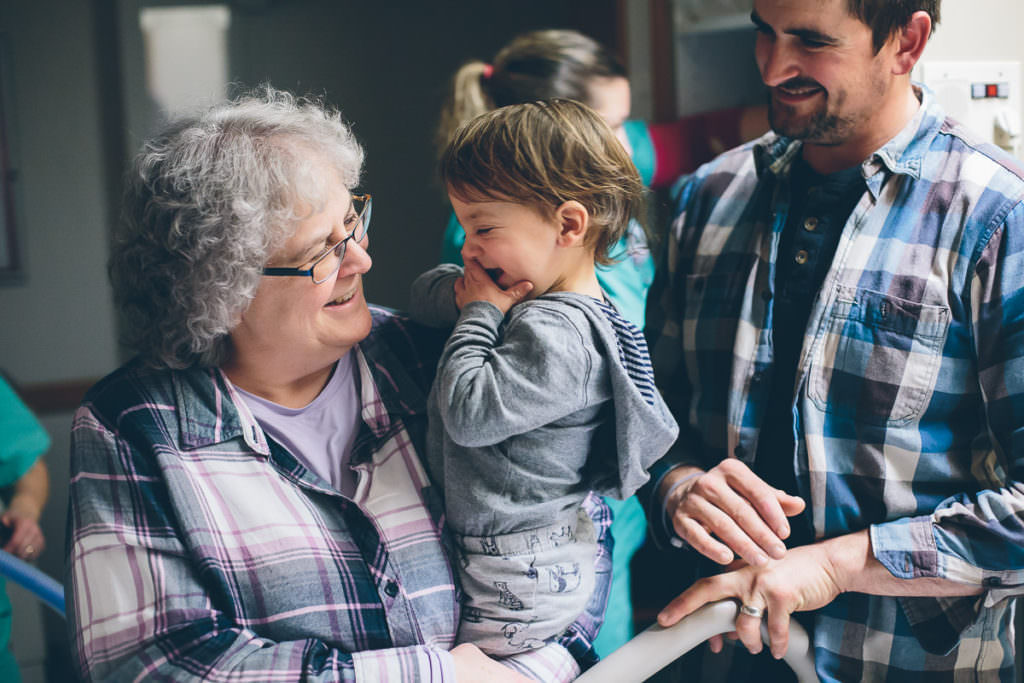 toddler smiling at his grandma who is holding him