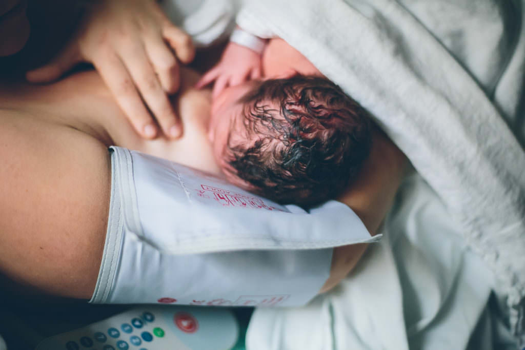 mom breastfeeding newborn baby with dark curly hair