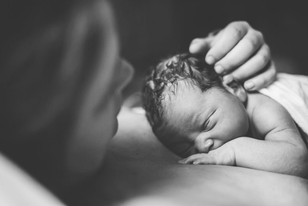 black and white image of baby laying on moms chest