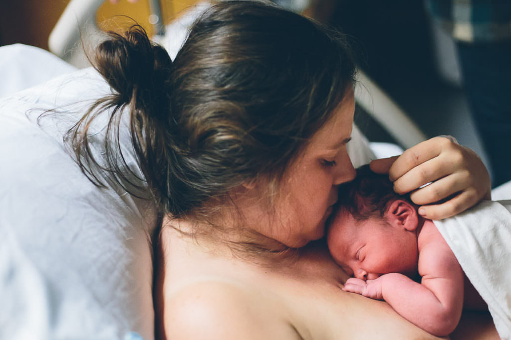 mom kissing newborn baby boy on the head
