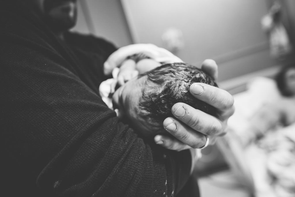 close up of dad holding newborn baby boys head