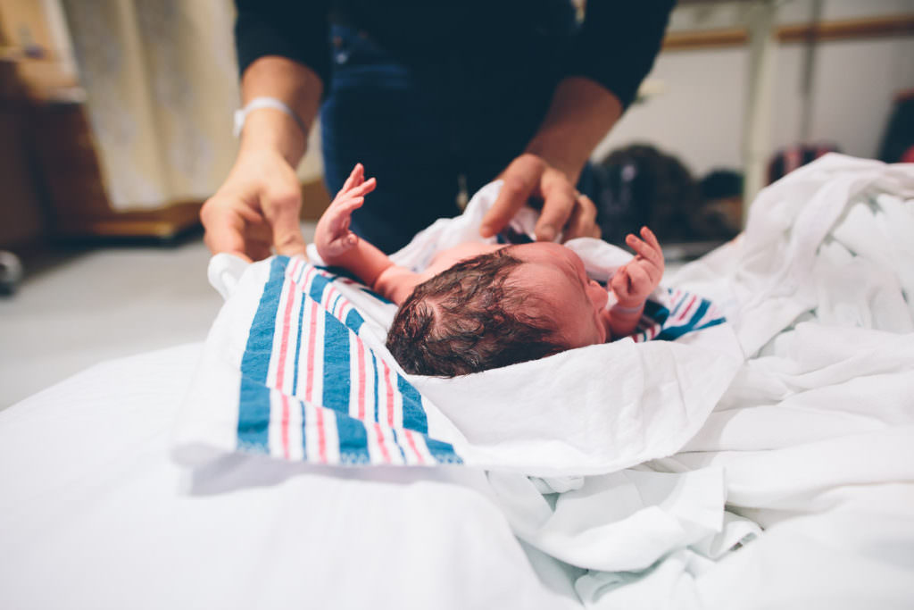 father wraps his newborn child in a swaddle blanket