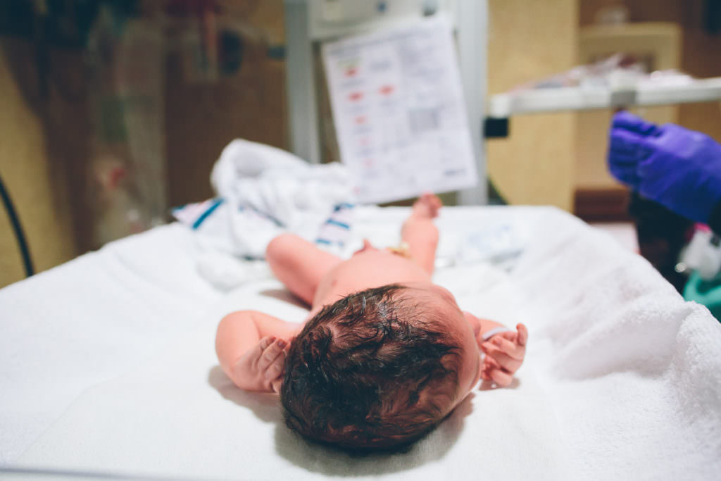 newborn laying on warmer getting a newborn check up after birth