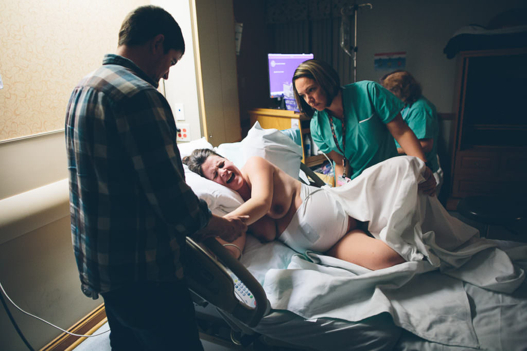 mom laboring on her side midwife holding her leg and dad holding her hand
