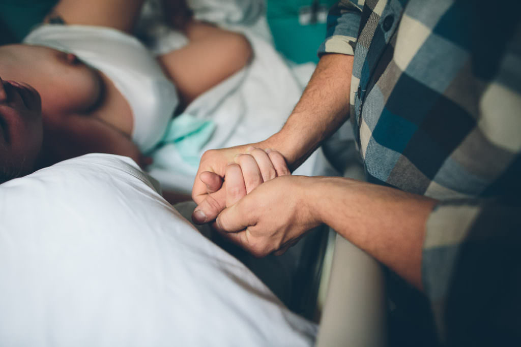 close up picture of couple holding hands during her labor