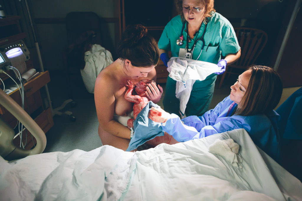 midwife and nurse bring blankets to wipe blood off baby just born
