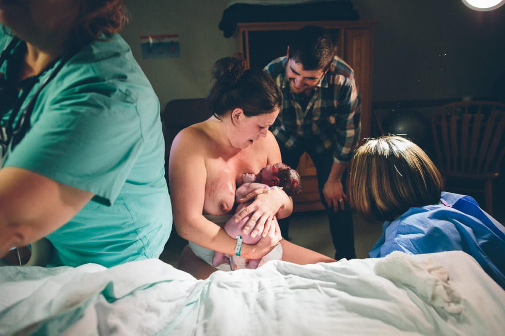 mom and dad look down sweetly at their baby that was just born at burdett birth center