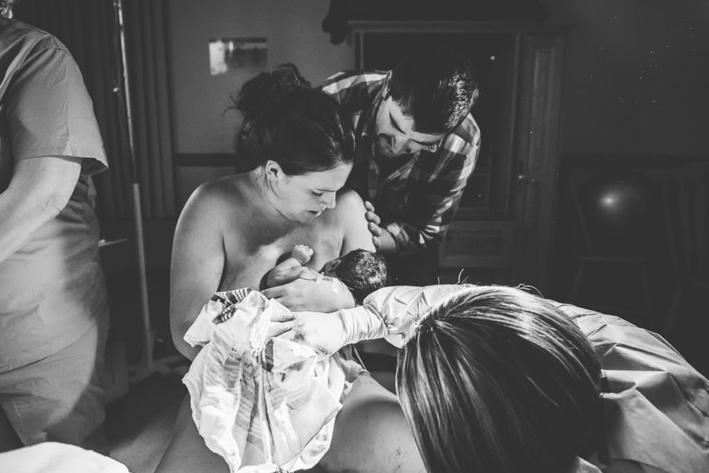 black and white picture of mom and dad looking down at their new baby