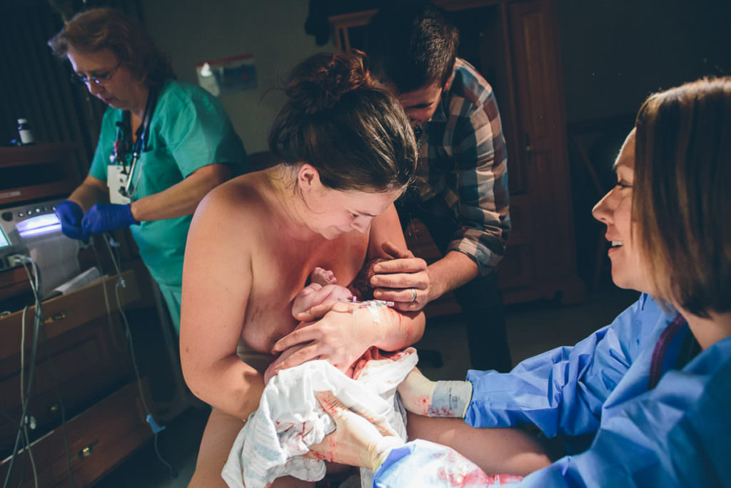dad holds new baby on his head while in the arms of his mom
