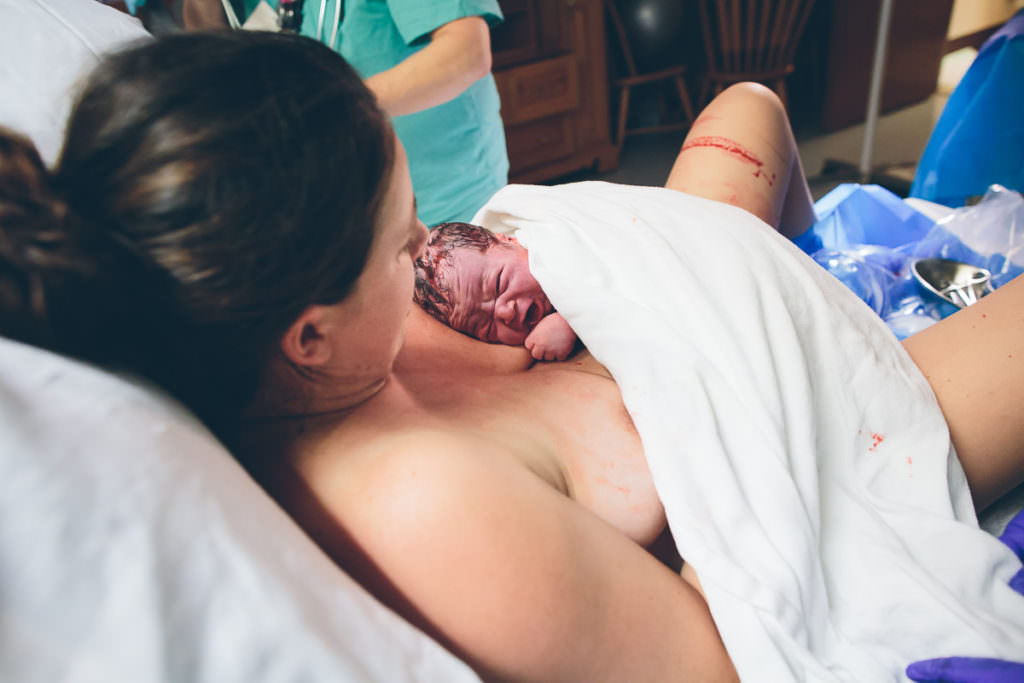 baby lays on moms chest while she delivers the placenta