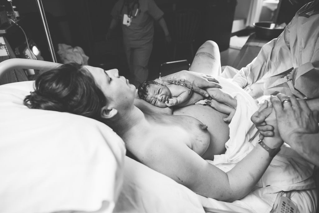 mom rests after giving birth while bright eyed baby lays on her chest