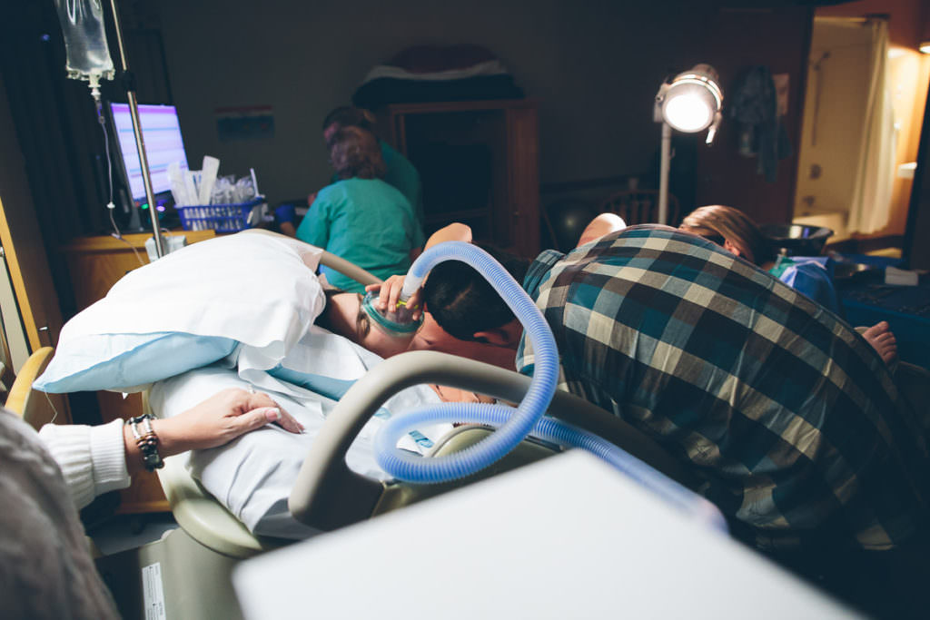 dad looks at baby while mom uses nitrous oxide while in pain after birth