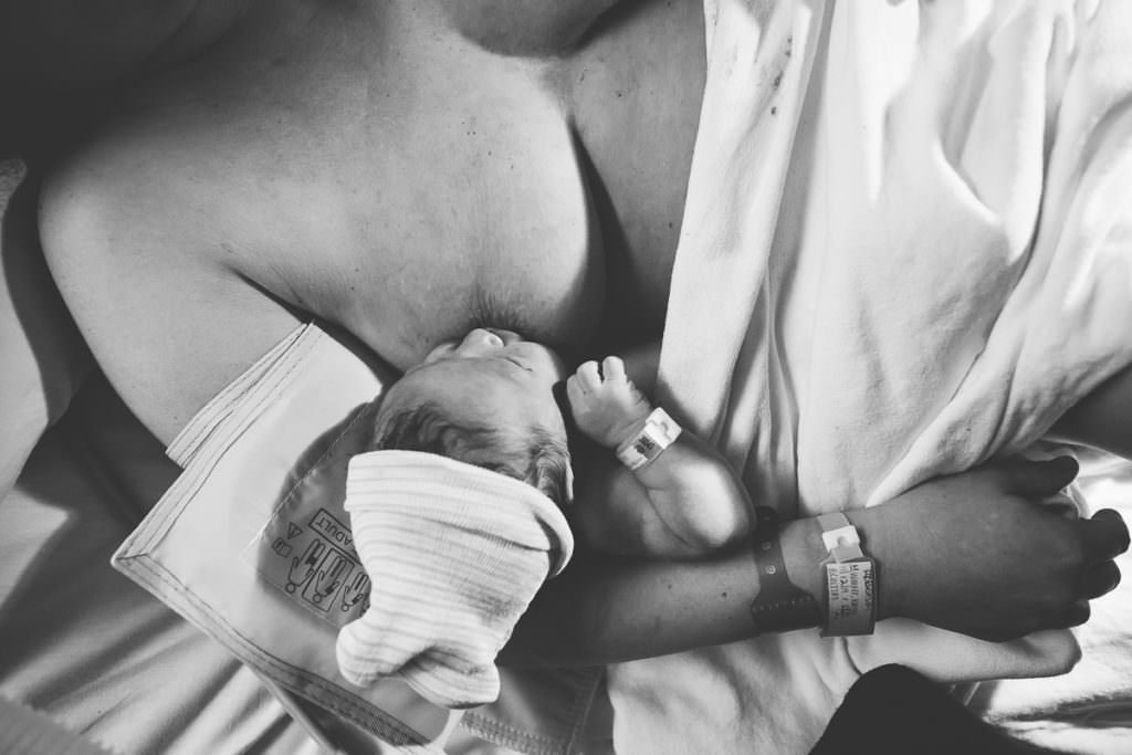 newborn baby boy nurses for the first time wearing hospital hat