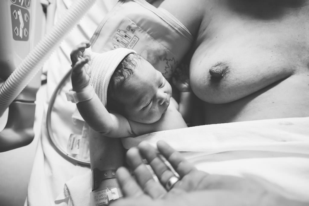 newborn baby boy arm flails while laying next to moms breast