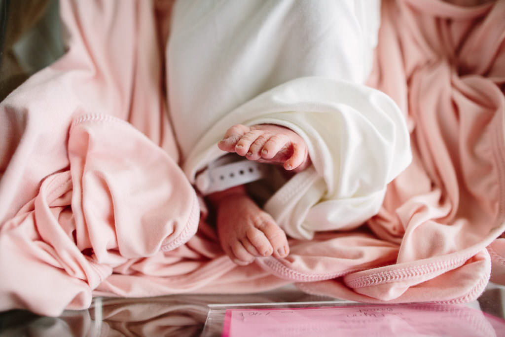 Baby feet during fresh 48 session sticking out of white newborn gown on top of pink blanket Saratoga Hospital