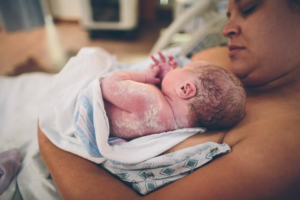 Newborn baby girl right after birth covered in vernix and wavy brown hair at Bellevue Hospital in Niskayuna New York