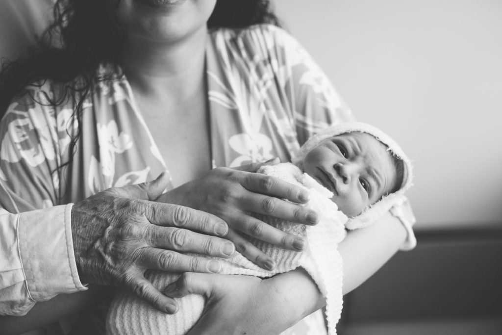 black and white picture of baby swaddled in moms arms during just born session