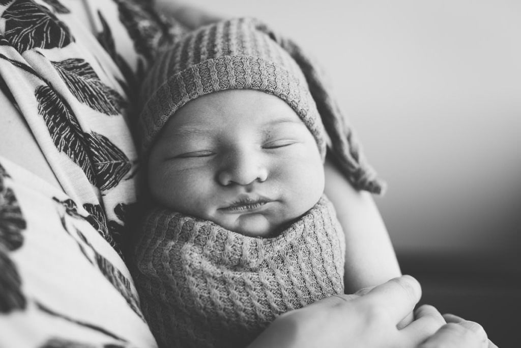 black and white image of sleeping baby boy with hat 