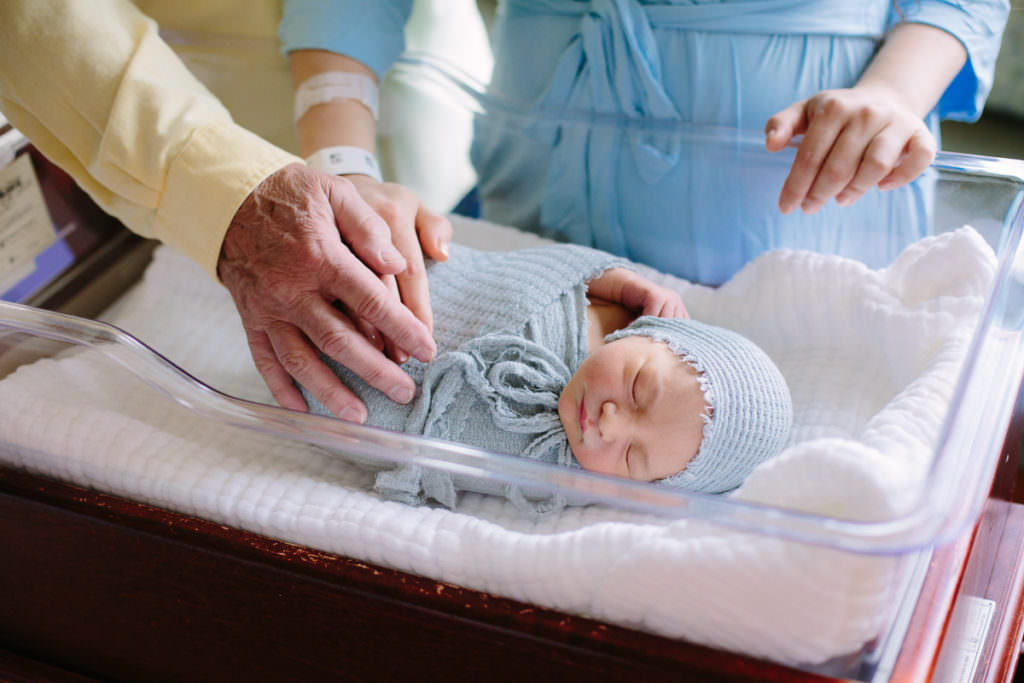 fresh 48 mom and dad put hands on newborn baby boy in Albany New York