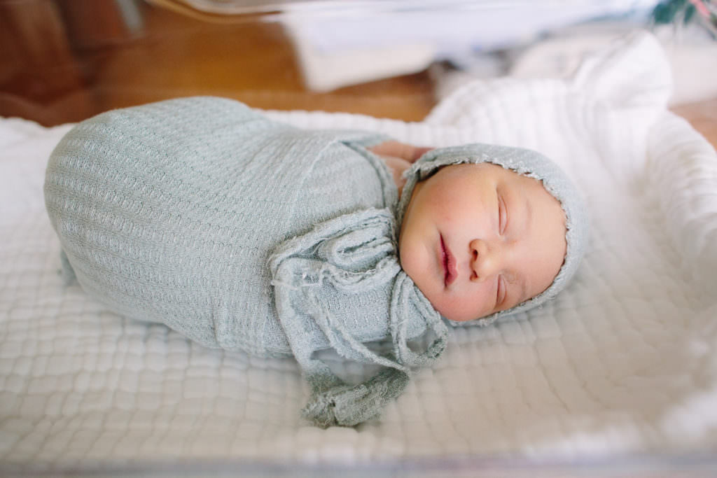 sleeping baby swaddled in blue blanket with matching hat 