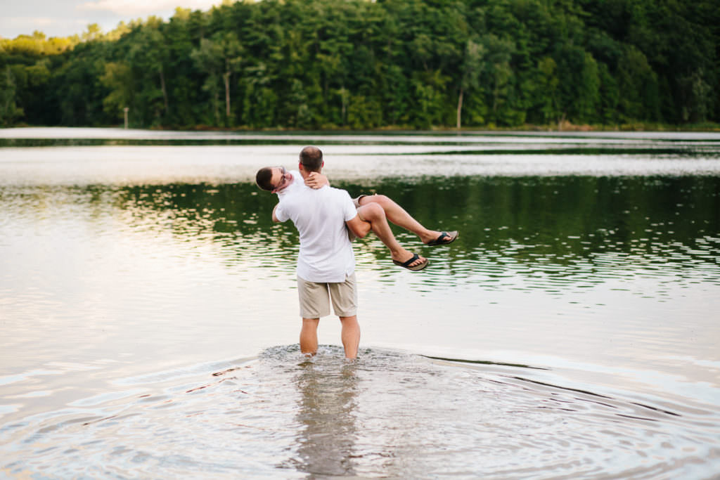 dad carrying fully clothed son into a lake