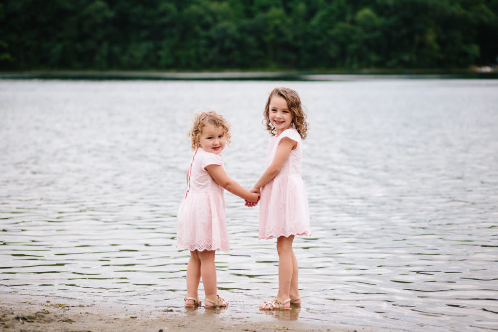 little girls in pink holding hands in the water at moreau lake new york