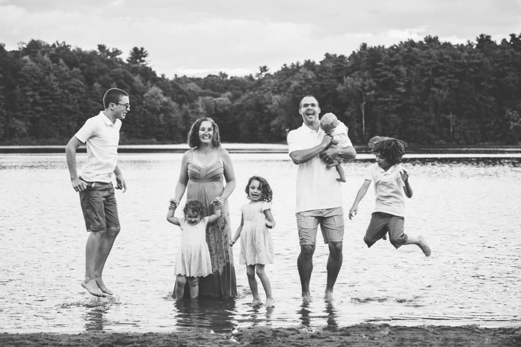 large family fully dressed play and jump in lake