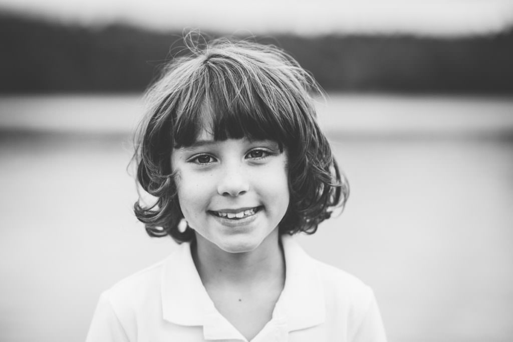 little boy with long brown hair and white collard shirt