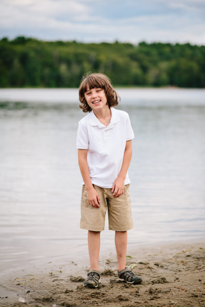 little boy standing on the beach at moreau lake