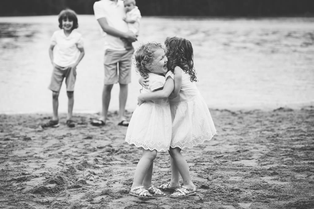 sisters hugging in white dresses on the beach