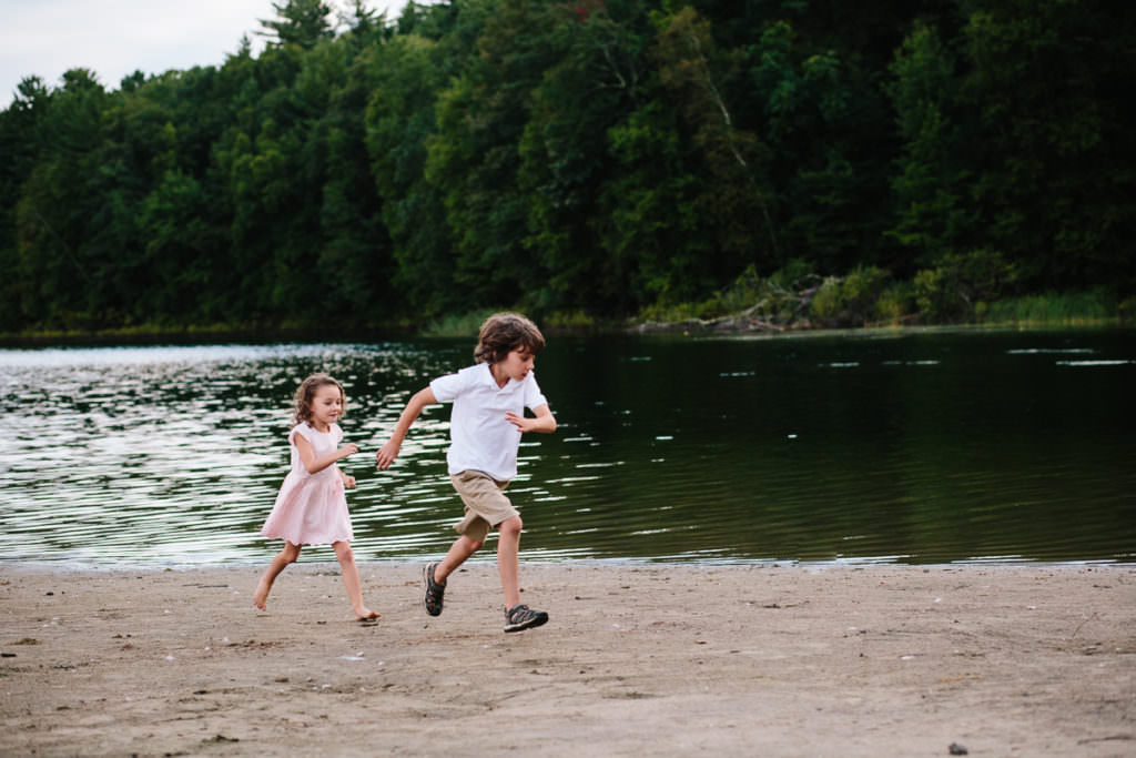 two young kids running on the beach at moreau lake