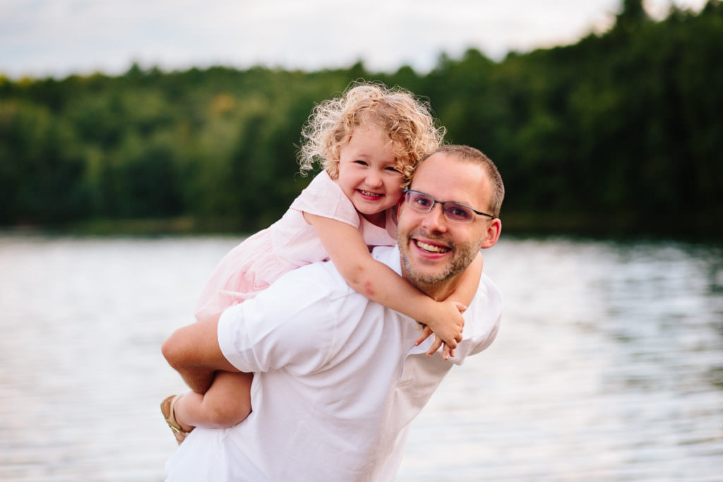 dad giving curly hair daughter a piggy back ride