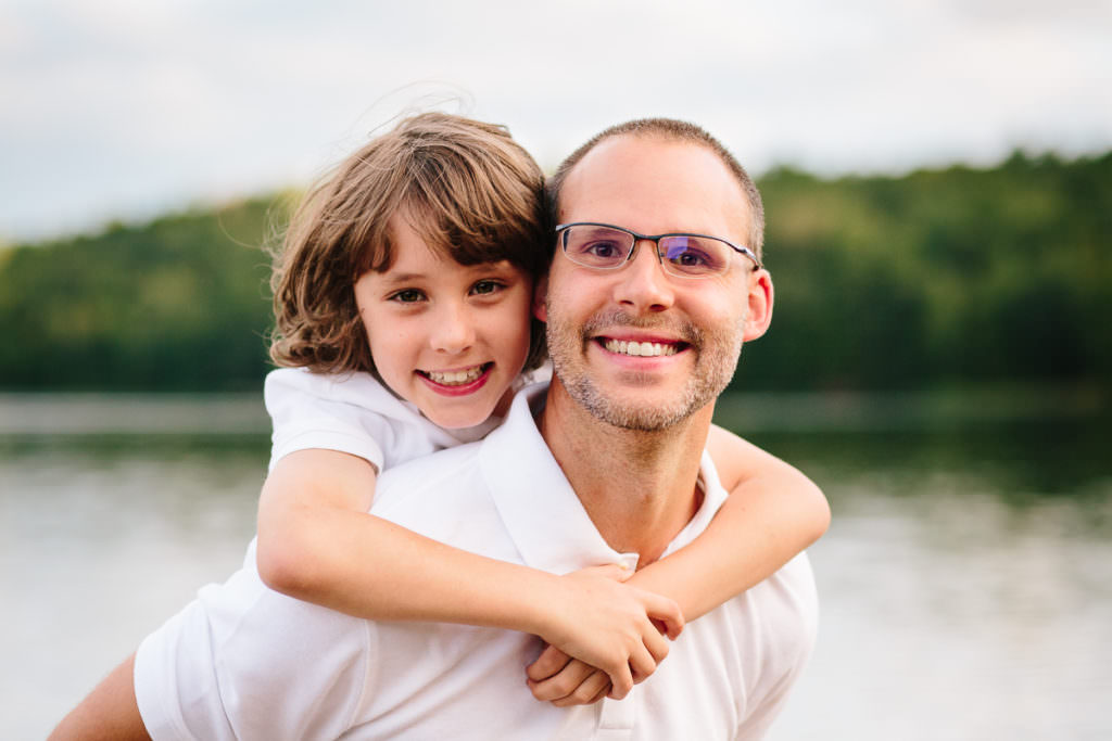 little boy with long brown hair on the back of his dad
