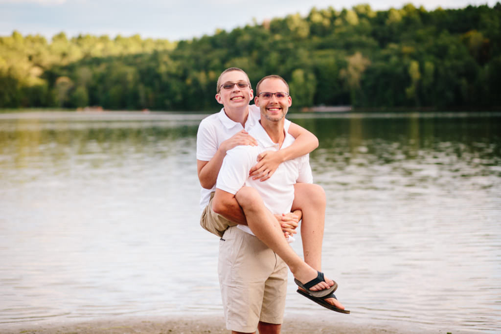 dad giving teenage son with glasses a piggy back ride
