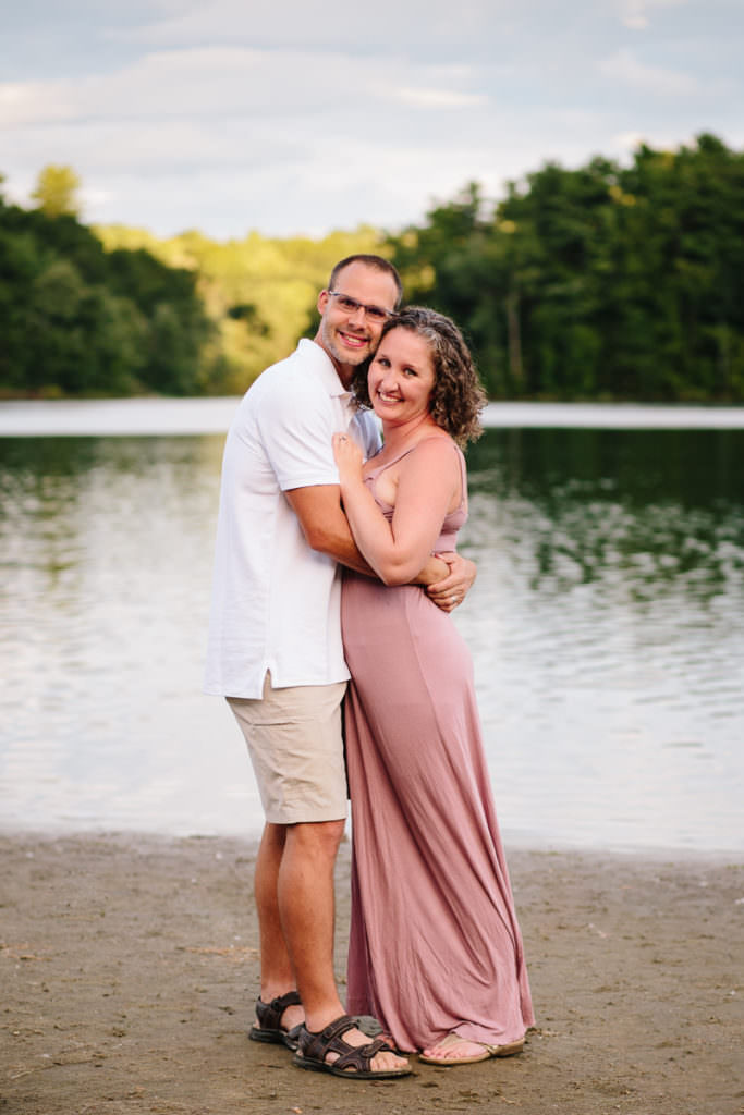husband and wife snuggle close with moreau lake in background