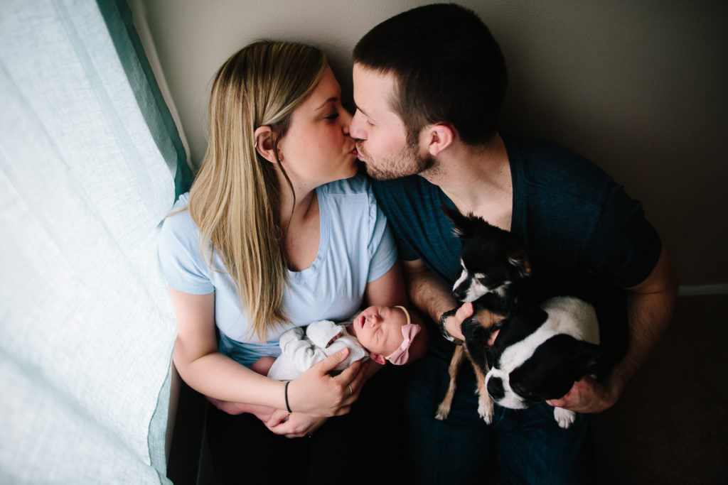 Lifestyle newborn pictures parents kissing holding newborn and dogs