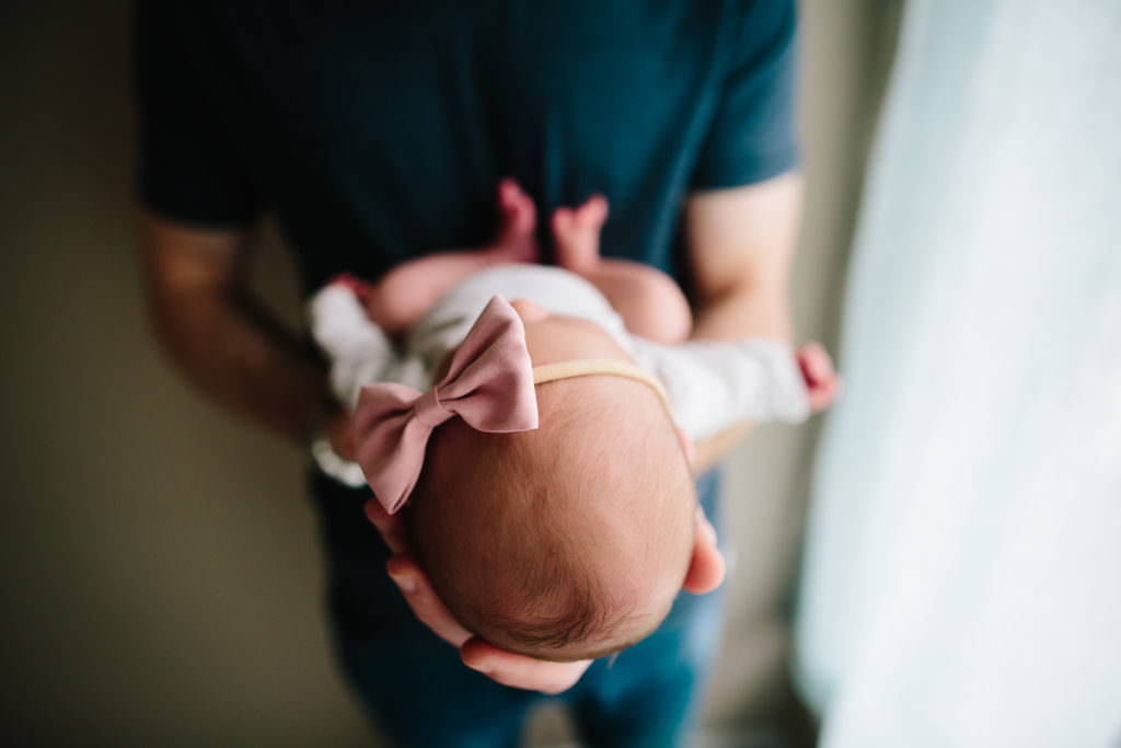 Albany NY lifestyle newborn photographer dad holding baby with bow