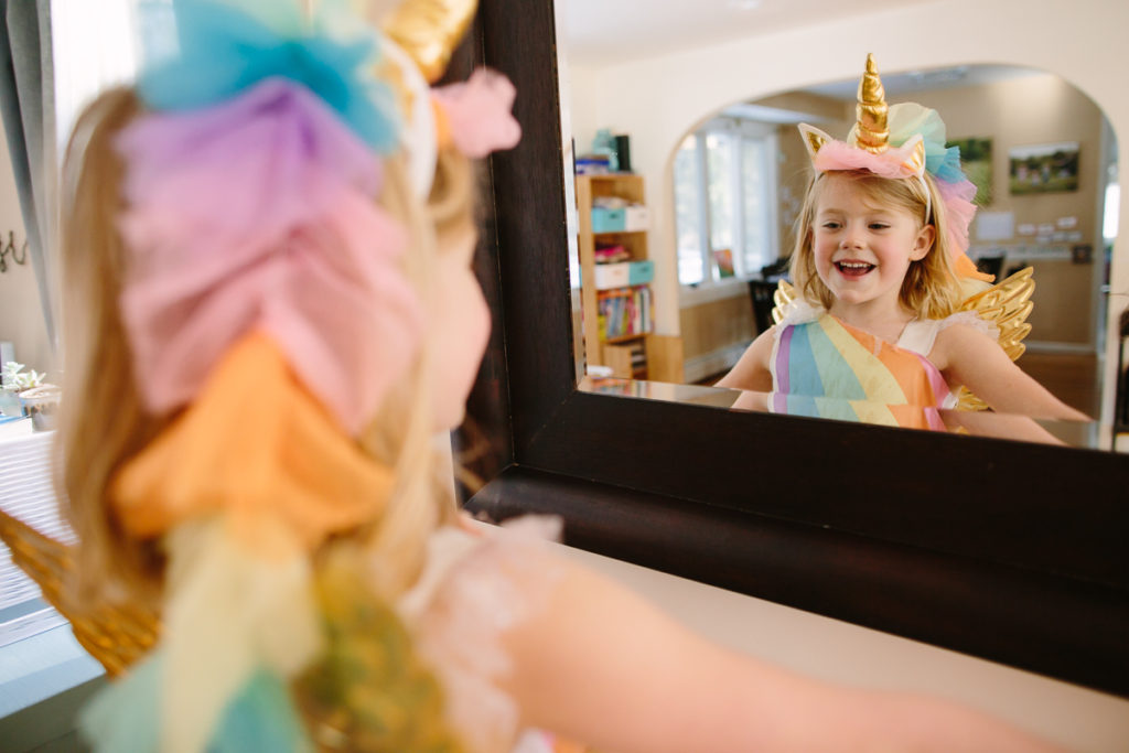 unicorn dress up looking in mirror child photographer