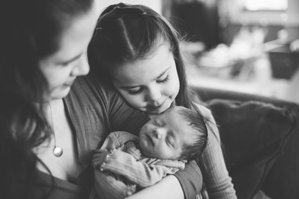 big sister looks adoringly at her new baby sister