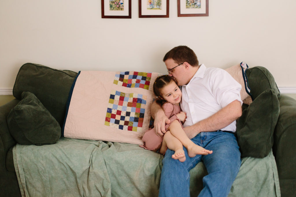 little girls snuggling with dad on the couch lifestyle family session