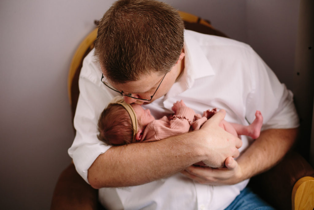 dad kissing newborn baby girl on the head