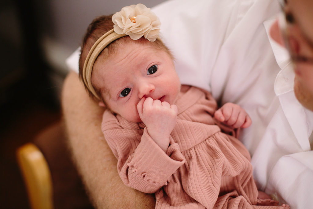 newborn baby with pink dress bow and eyes open