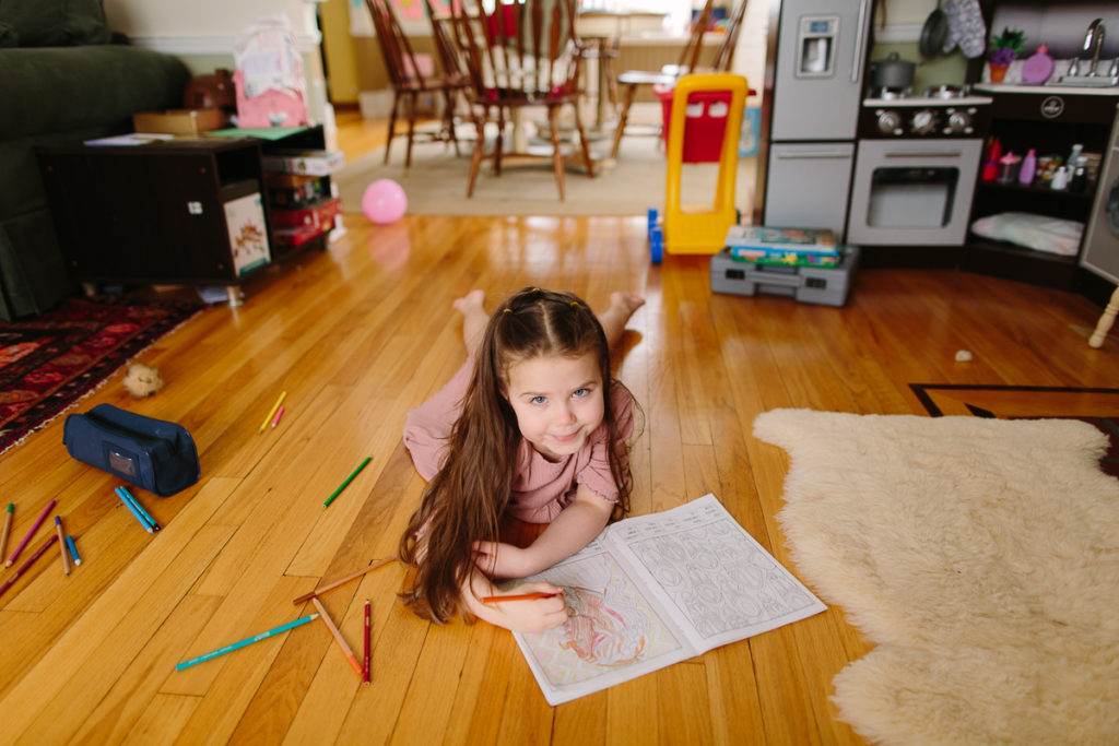 little girl coloring during lifestyle newborn session