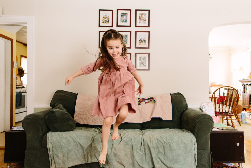lifestyle photography little girl jumping off the couch