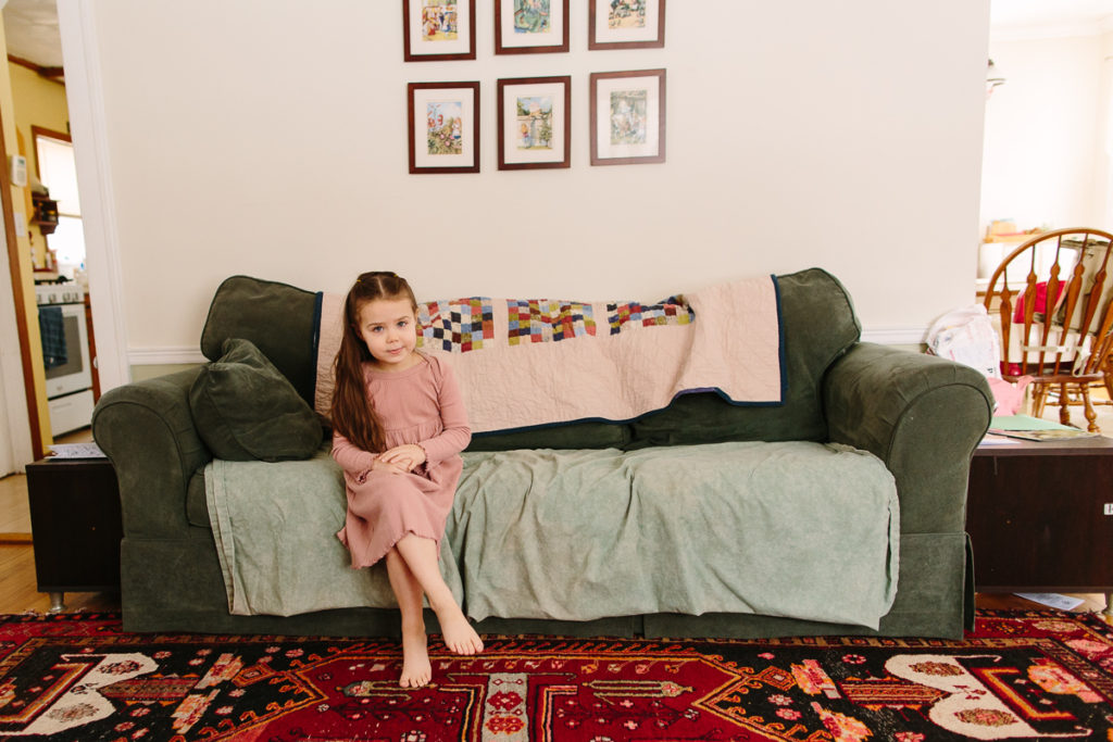 little girl sits on couch during lifestyle family session