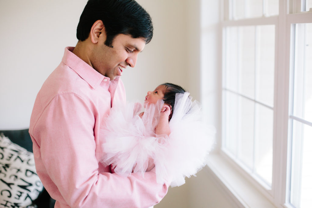 dad holding newborn baby girl in tutu