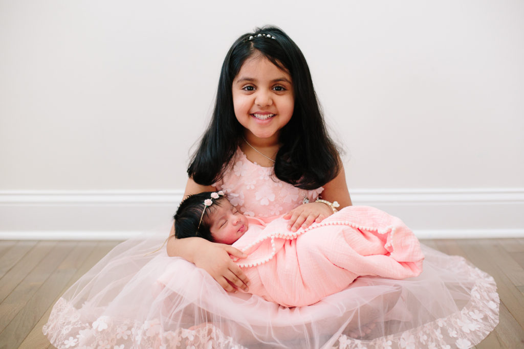 big sister holding baby sister in tutu